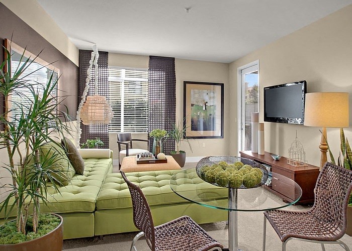 a living room with a green couch and a glass table
