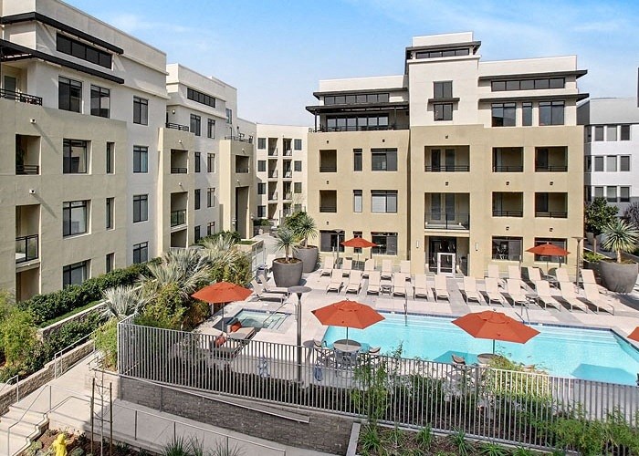 a swimming pool with chaise lounge chairs and umbrellas in front of a building