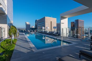 Resort-style pool deck with daybeds and panoramic skyline views  at Stanza Little Italy, San Diego, 92101
