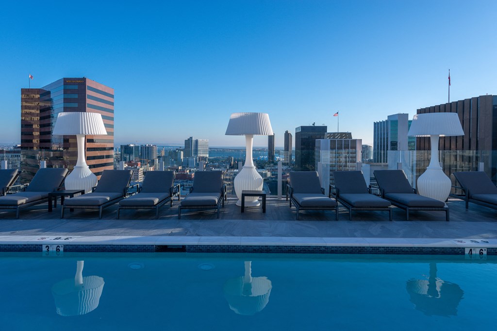 a pool with lounge chairs and lamps on top of a building at Stanza Little Italy, California, 92101
