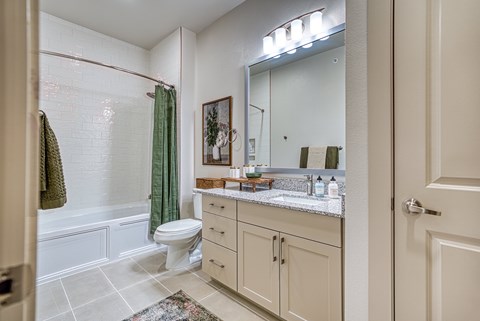 A bathroom with a toilet, sink, and mirror.