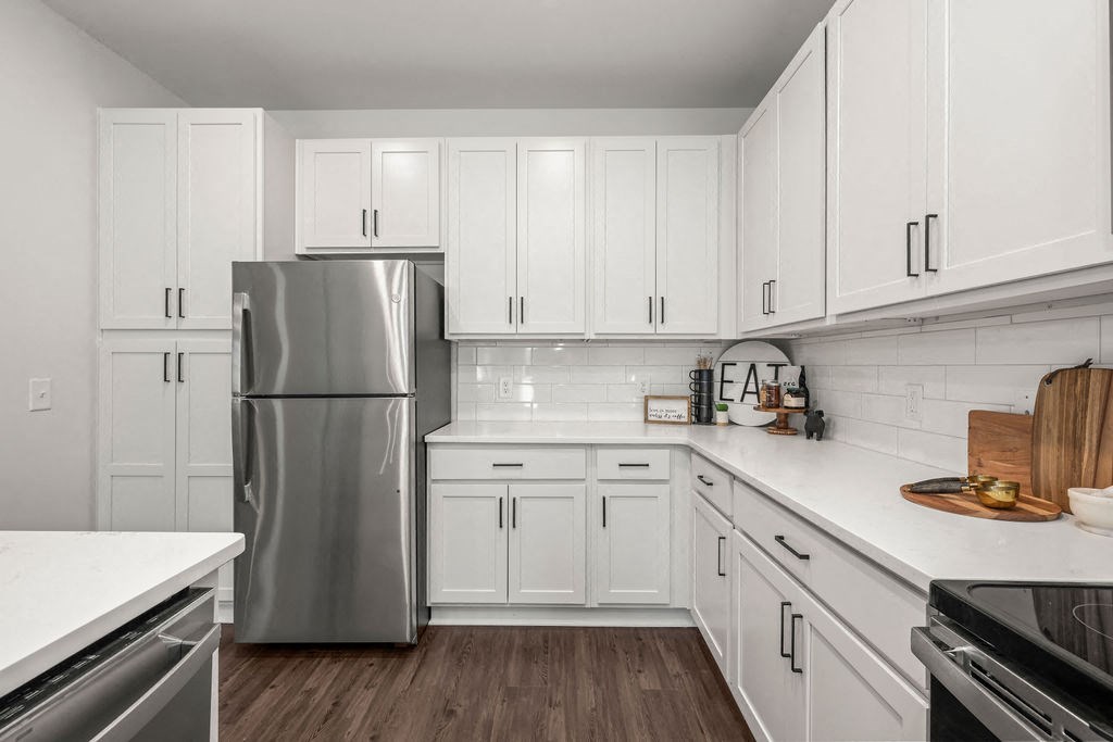 a kitchen with white cabinets and a stainless steel refrigerator