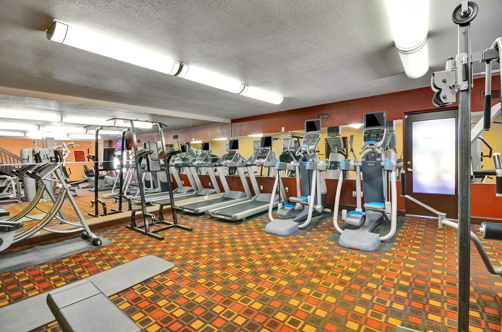 A gym with a variety of equipment including treadmills, weights, and exercise machines.
