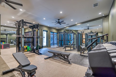 A spacious gym with a variety of equipment including a bench, weights, and a mirror.