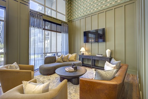 A living room with a brown leather couch, a coffee table, and a flat screen TV mounted on the wall.