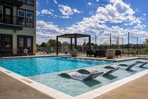 a swimming pool at a hotel with a blue sky and clouds
