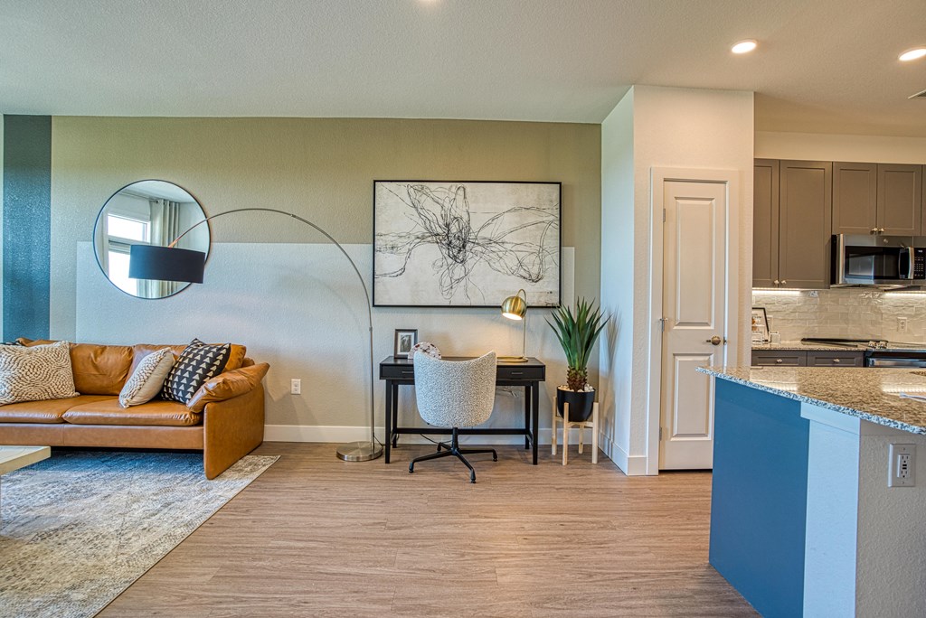 a living room and kitchen with a desk and a couch