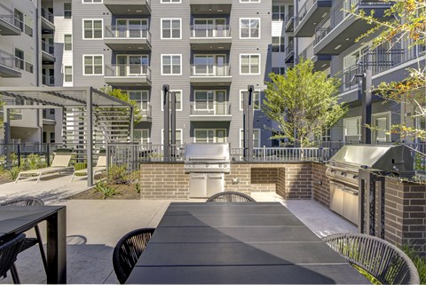 A patio with a table and chairs is surrounded by apartment buildings.