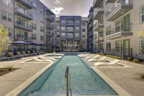 A swimming pool in the middle of a courtyard surrounded by buildings.