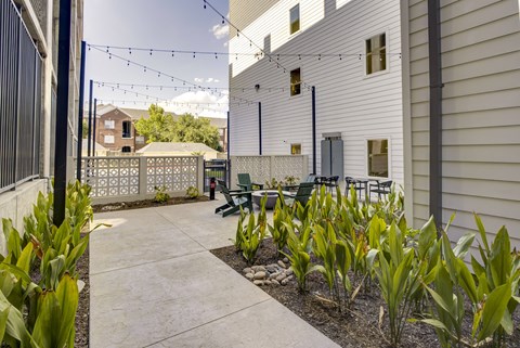 A patio with a table and chairs is surrounded by plants.