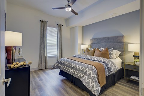 A bedroom with a large bed and a ceiling fan.