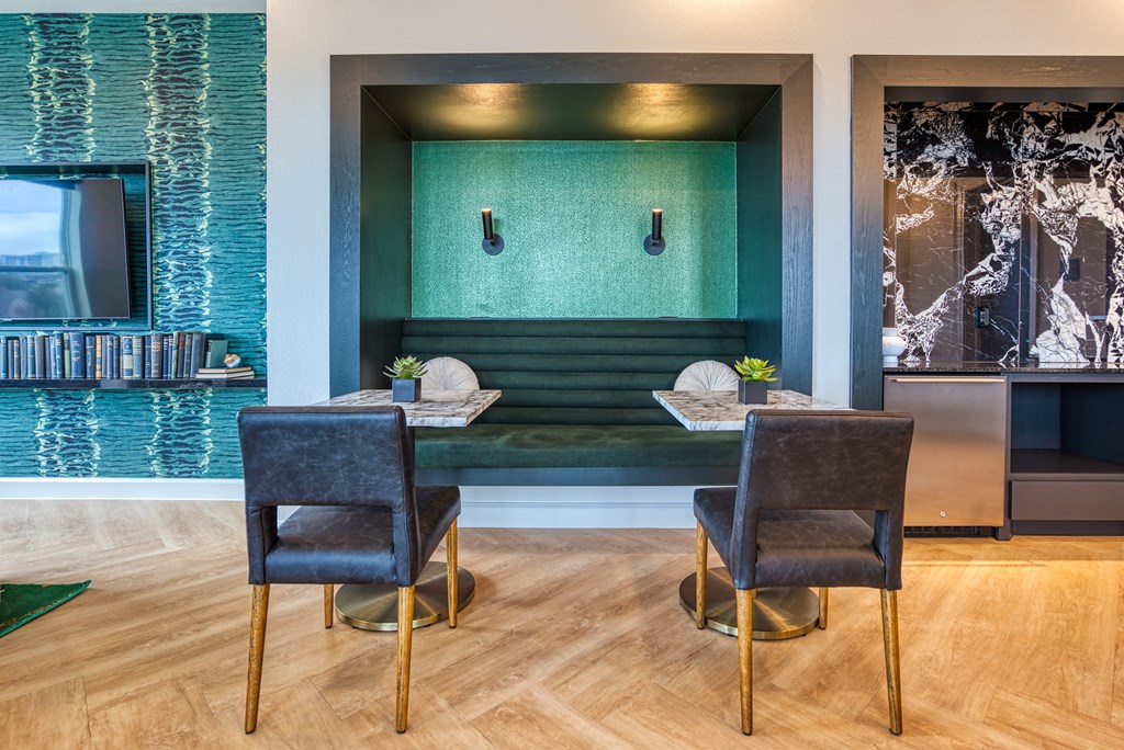 a living room with a table and two chairs in front of a green accent wall