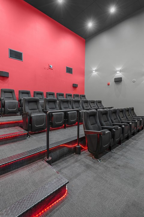 A row of black cinema seats with red lighting underneath them.