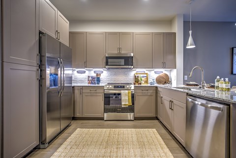 A kitchen with a refrigerator, oven, and sink.