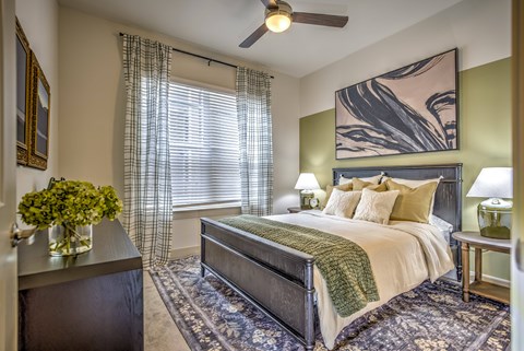 A bedroom with a bed, nightstand, and a painting on the wall.