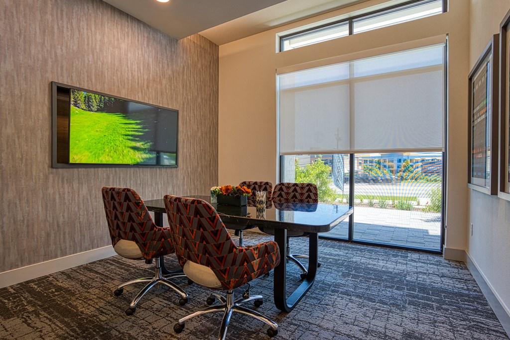 a conference room with a table and chairs and a tv on the wall