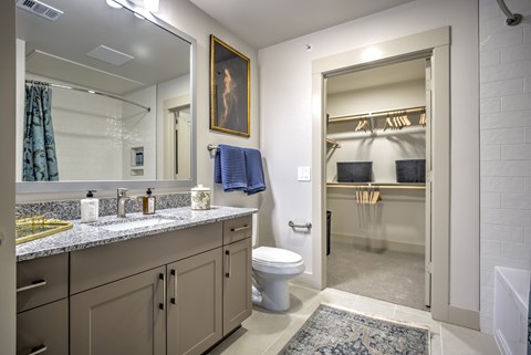 A bathroom with a toilet, sink, and mirror.