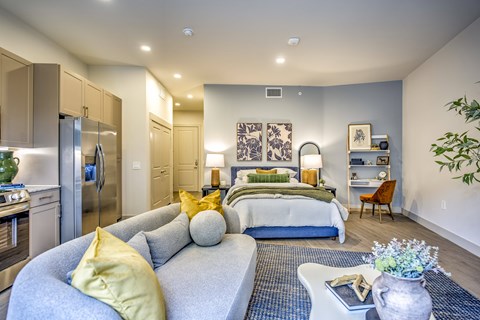 A modern bedroom with a grey couch and a bed with a blue and white comforter.
