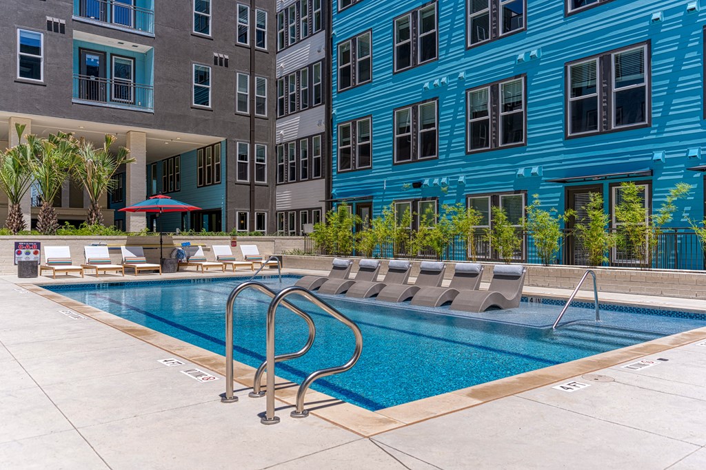 a swimming pool with chaise lounge chairs and a blue building in the background