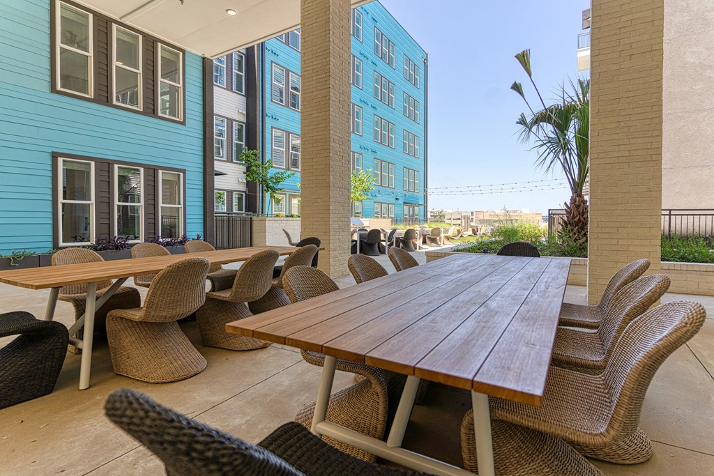 a patio with a wooden table and wicker chairs