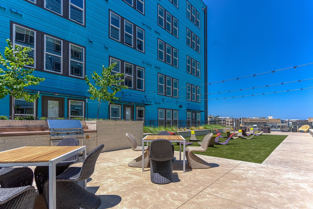 a patio with tables and chairs on the side of a building