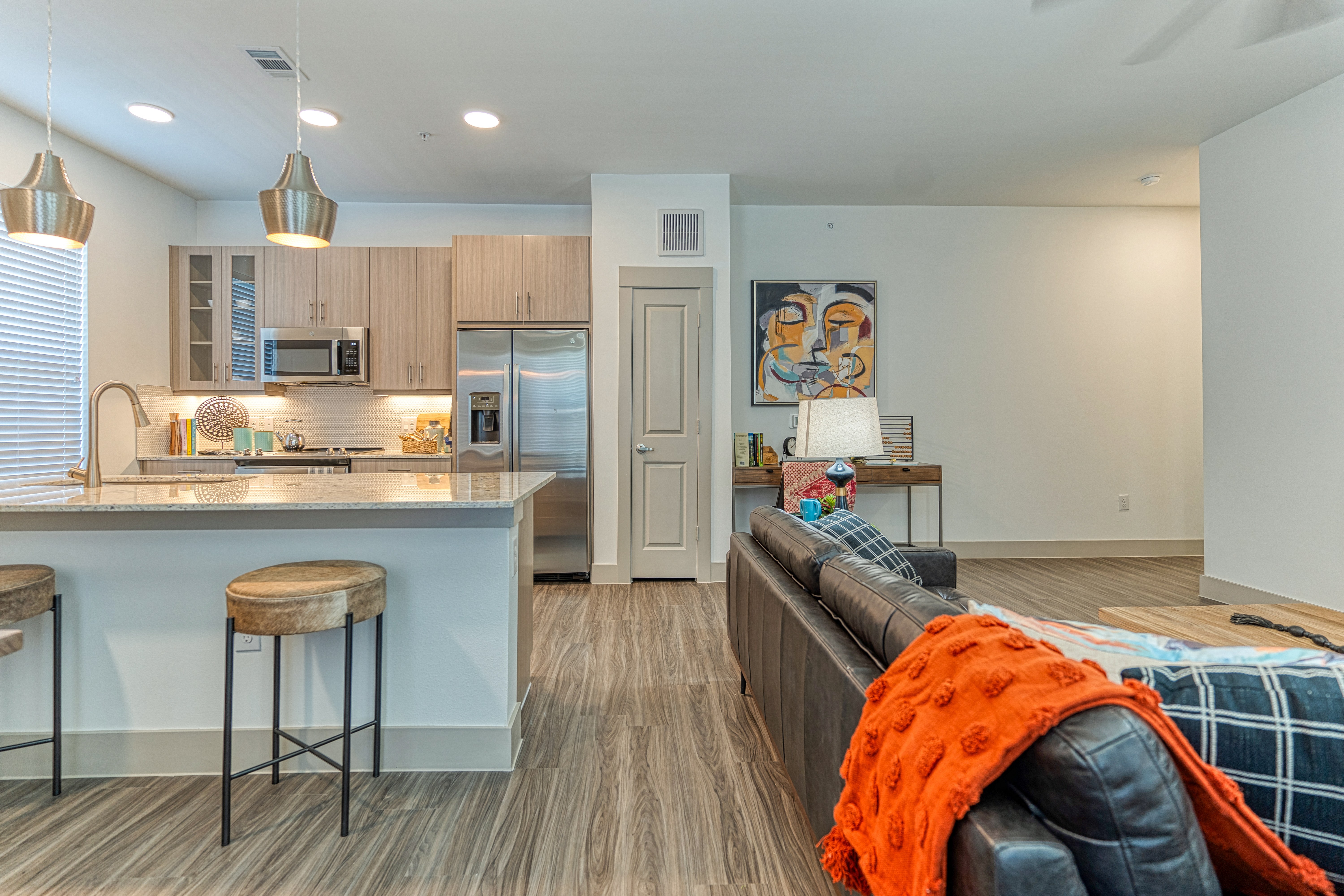 a living room and kitchen with a couch and two stools