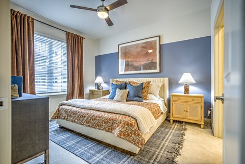 A bedroom with a large bed and a ceiling fan.