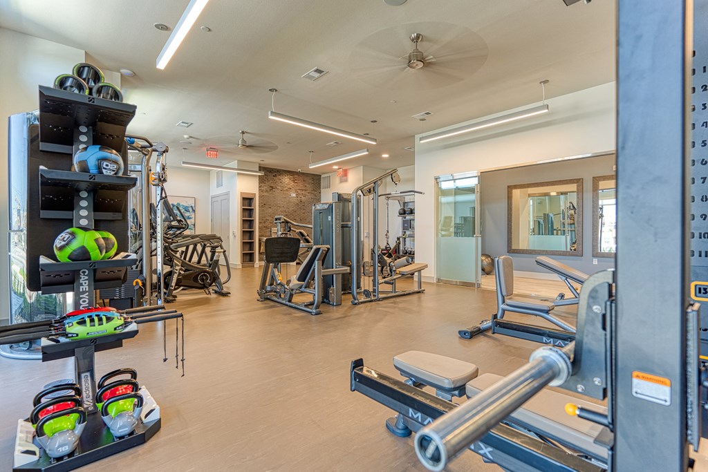 a spacious fitness center with cardio equipment and weights