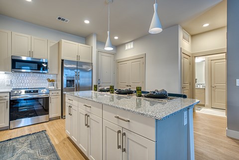 A kitchen with a granite countertop and stainless steel appliances.