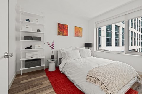 A bedroom with a large bed and a red rug.
