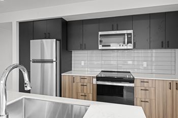 a kitchen with black cabinets and stainless steel appliances at Ion Town Center, Shoreline, WA