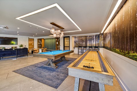 A pool table with a blue cloth and a wooden rack is in the middle of the room.