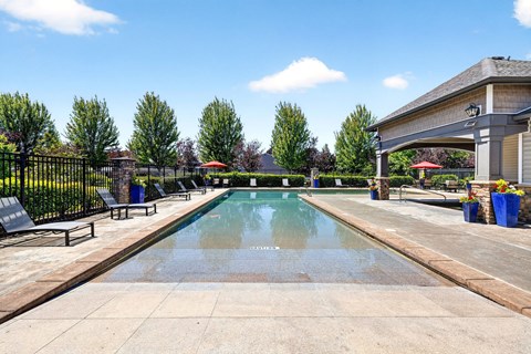 A large outdoor swimming pool surrounded by trees and lounge chairs.