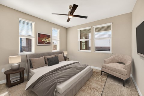 A bedroom with a large bed, a chair, and a ceiling fan.
