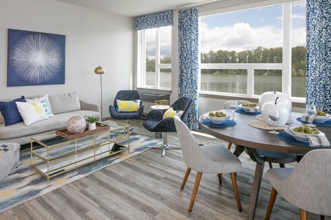 A modern living room with a grey sofa, a coffee table, and a dining table set for a meal.