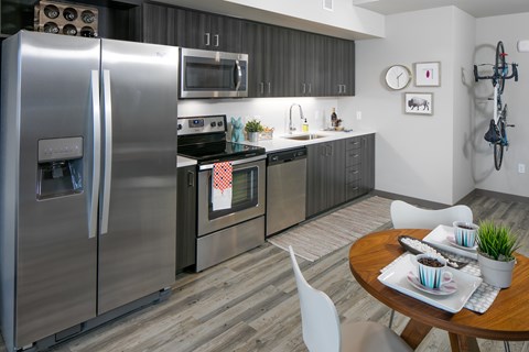 A modern kitchen with a stainless steel refrigerator and a dining table set for two.