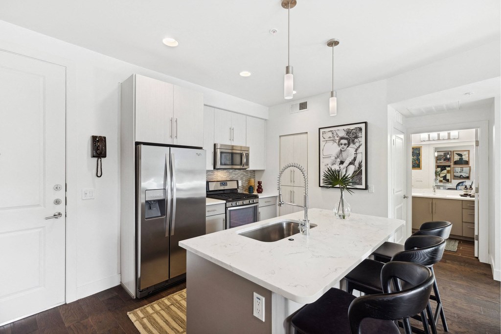 A kitchen with a white counter top and a refrigerator.