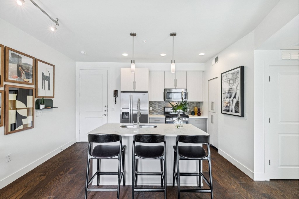 A kitchen with a white table and black chairs.