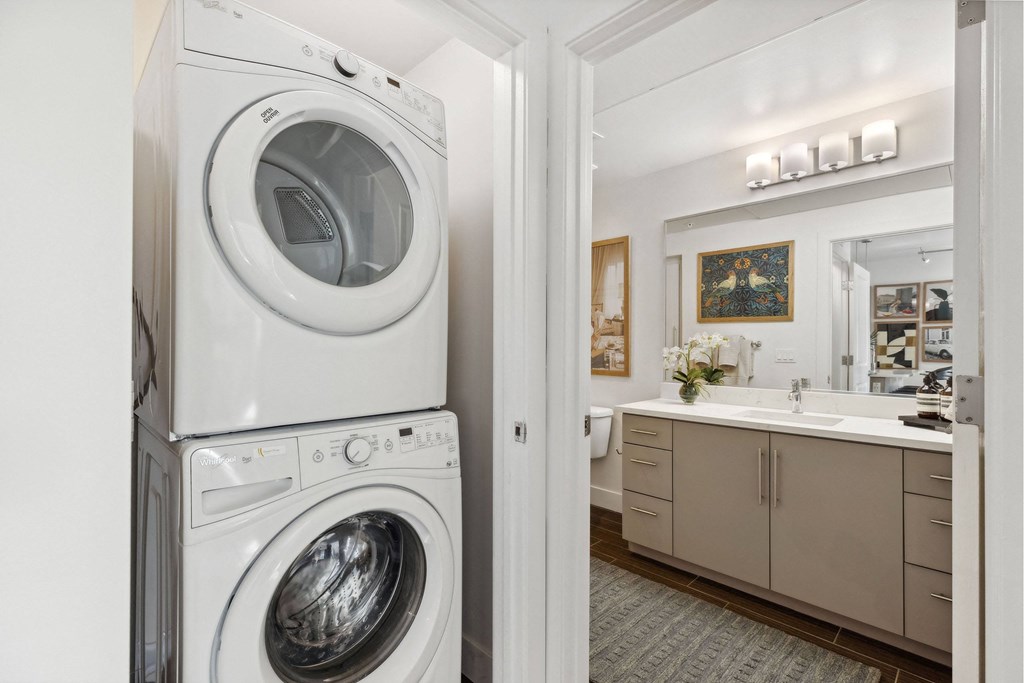 A white washing machine and dryer stacked on top of each other in a laundry room.