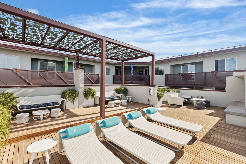 A sunny day at the rooftop patio with white lounge chairs and blue cushions.