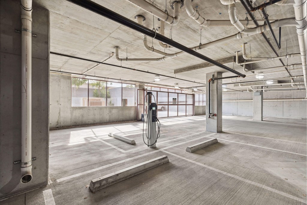 A parking garage with a concrete floor and walls, and a concrete pillar on the left.