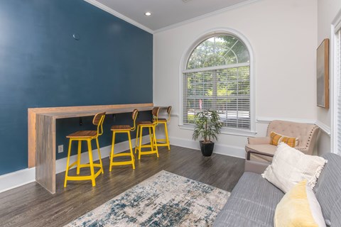 A living room with a grey couch, a wooden table and yellow chairs.