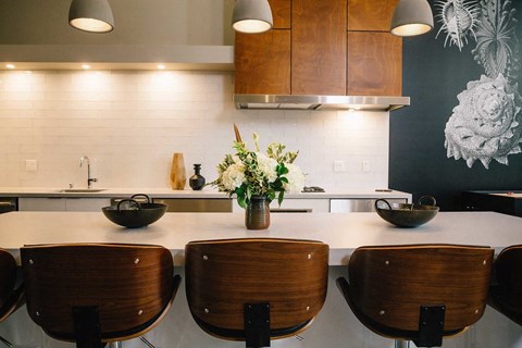 A kitchen with a white counter top and wooden chairs.