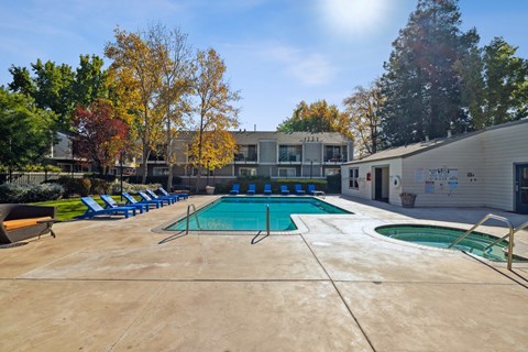 A large outdoor swimming pool surrounded by trees and a building.