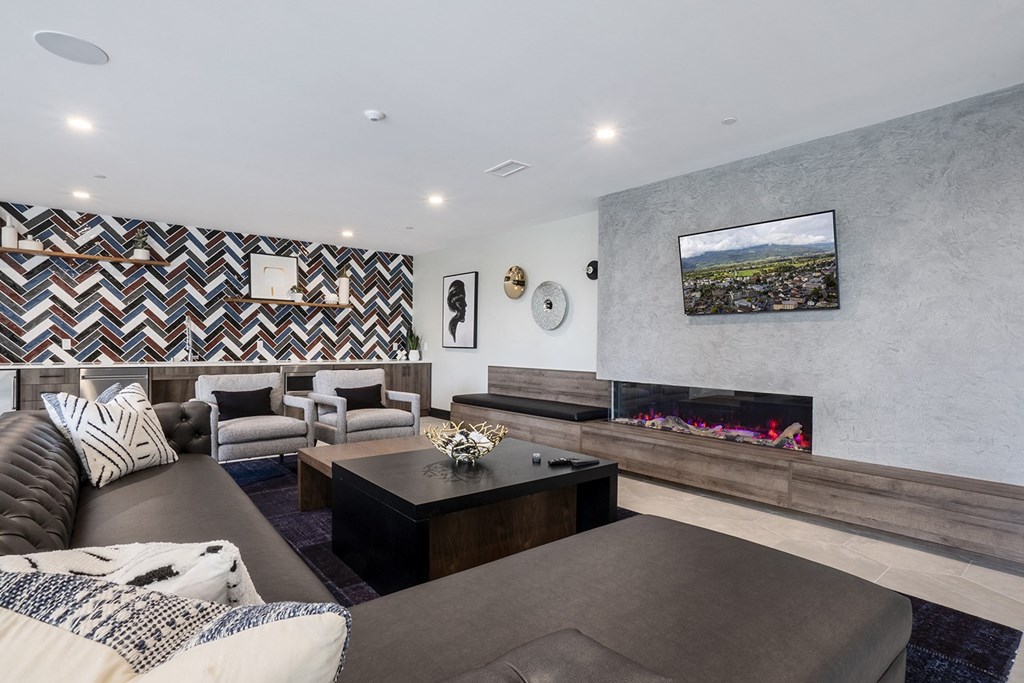 indoor lounge space with sofas and a large fire place. TV on wall