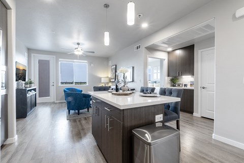 A modern kitchen with a blue chair and a stainless steel trash can.