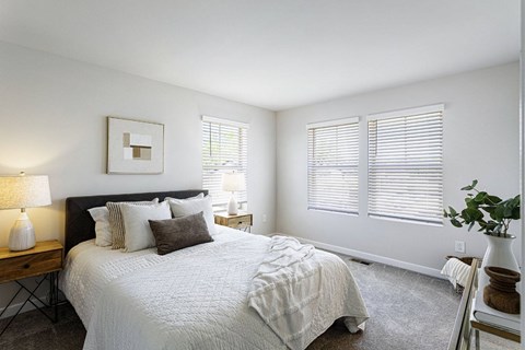 A bedroom with a large bed and a lamp on a side table.