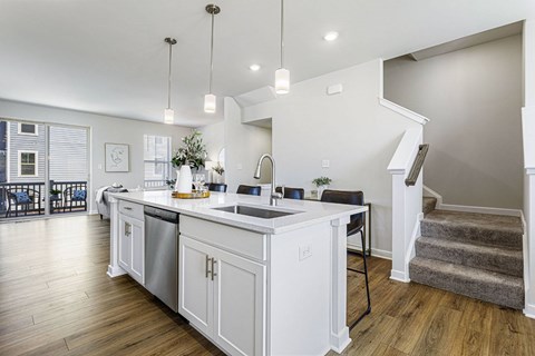 A modern kitchen with white cabinets and a wooden floor.