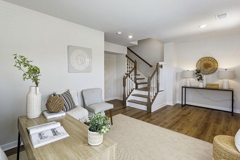 A living room with a staircase and a table with a plant on it.