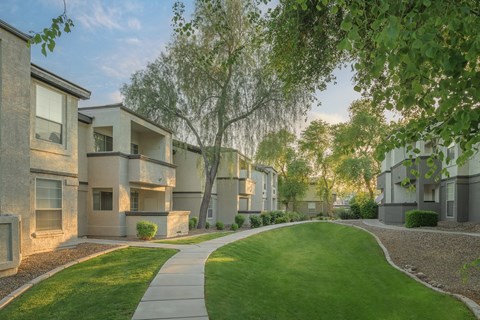 an exterior view of an apartment complex with green grass and trees